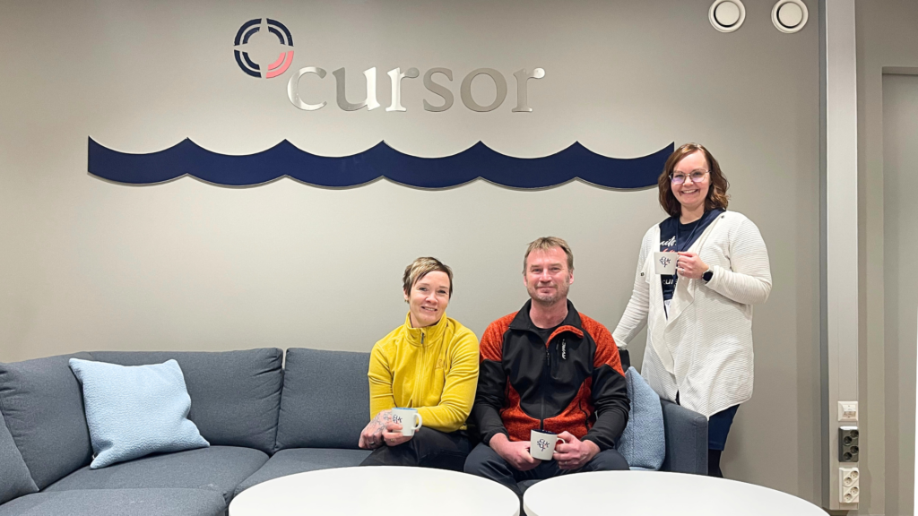 Katja Kormu sekä Jami Remontoinnin yrittäjät istumassa sohvalla kahvikupit kädessään. Kaikki hymyilevät kohti kameraa. Takana on Cursorin logo.